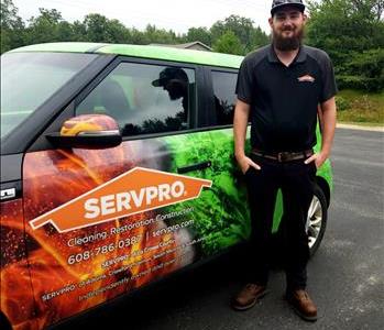 SERVPRO employee in front of SERVPRO sign