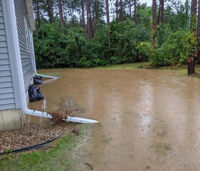 High brown water up against a blue home. 