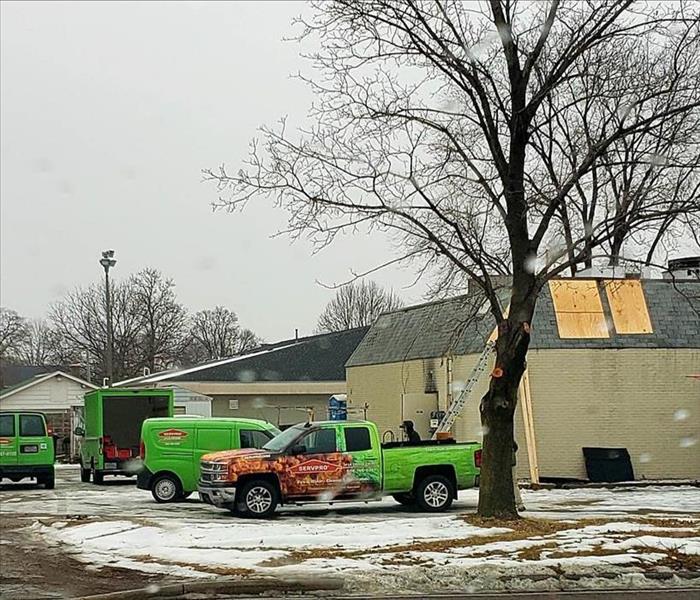Green SERVPRO vehicles parked outside of a building.
