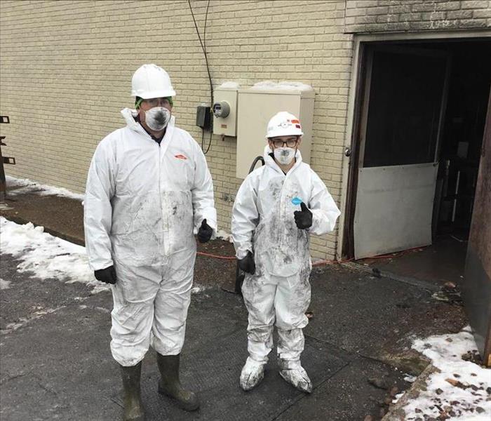 Two men in PPE standing outside.