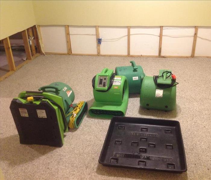 Green air movers on the floor of a room with flood cuts. 