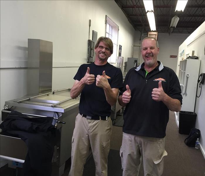 Two men smiling for a photo with their thumbs up.