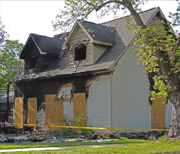 The exterior of a house with significant fire and soot damage.